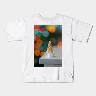 Christmas tree shaped candle on wooden cupboard against christmas lights Kids T-Shirt